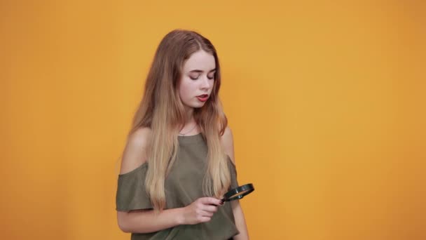 Femeie tânără în cămașă de modă care deține o lupă, arătând serios — Videoclip de stoc