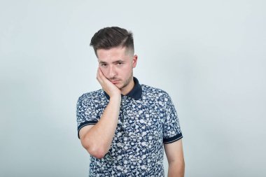 Yorgun adam, elini yüzüne koyuyor. Sıkıcı görünüyor, üzgün, konuyu düşünüyor.