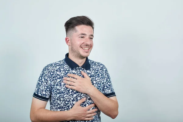 Ritratto di giovane uomo piacevole e sorridente in camicia casual che si tiene per mano sul petto — Foto Stock