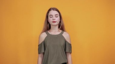 Güzel, rahat gömlekli bir kadın. Gözleri açık bakıyor, elini kenara çekiyor.