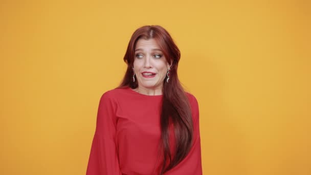 Red lady biting her lips as she is afraid of someone near yellow wall. — Stock Video