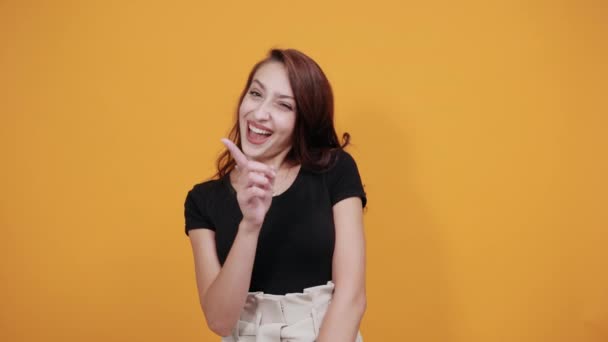Приваблива молода жінка в чорній повсякденній сорочці, вказуючи пальцем вгору, посміхаючись — стокове відео