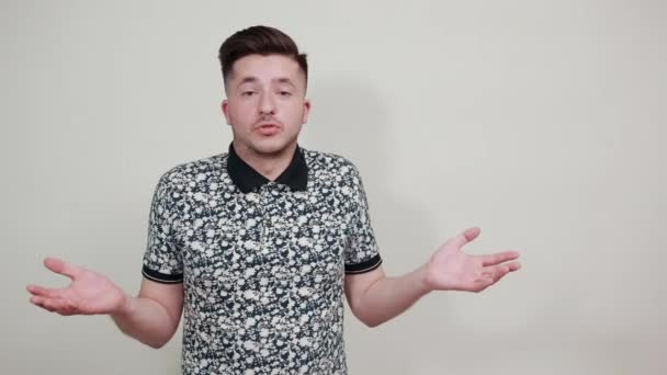 Droevige vrolijke jongeman in casual shirt, direct kijkend, handen spreidend — Stockvideo