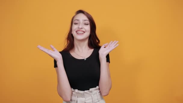 Pretty young woman in black shirt holding hand on cheeks, looking happy — Stock Video