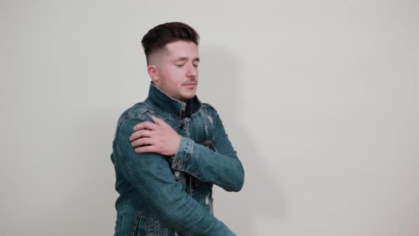 Mężczyzna trzymający jedną rękę na ramieniu, drugą za plecami, grymas bólu — Wideo stockowe