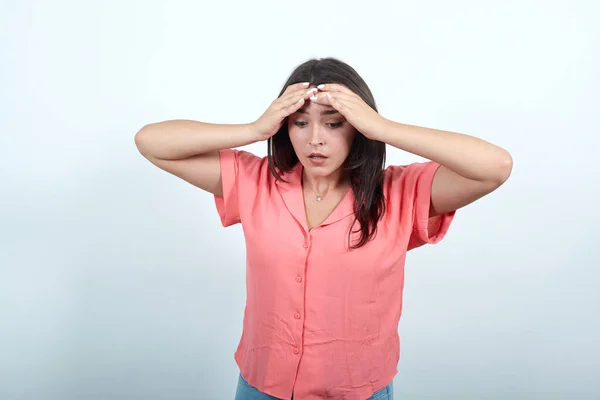 Señora atractiva en camisa rosa manteniendo la mano en la cabeza, buscando cansado, confundido — Foto de Stock