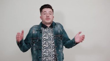 Moda gömlekli genç adam kollarını açıyor, omuzlarını kaldırıyor.