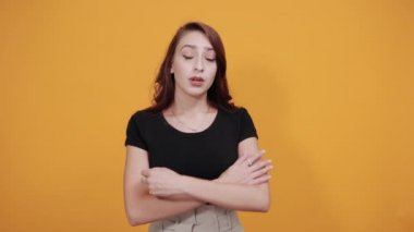 Siyah gömlekli hayal kırıklığına uğramış bir kadın, ellerini göğsünde çapraz yapmış, üzgün görünüyor.