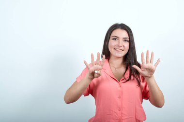 Beyaz kadın kameraya dokuz parmak gösteriyor.