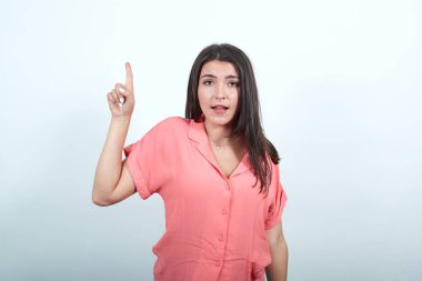 Esmer, beyaz, genç bir kadın yukarı bakıyor, kafası karışık.