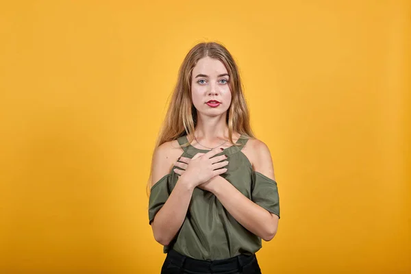 Портрет улыбающейся молодой женщины, держащей руки на груди, сердце изолировано на стене — стоковое фото