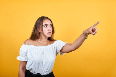 Hayal kırıklığına uğramış genç bir kadın mesafeyi işaret ediyor, ciddi görünüyor.