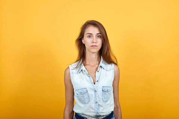 Mujer joven decepcionada en camisa de mezclilla azul mirando estricto y serio —  Fotos de Stock