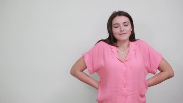Serieuze dame in roze shirt houden hand op hoofd, houden andere hand achter de rug — Stockvideo