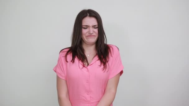 Disappointed young woman in pink shirt keeping thumbs down, looking directly — 图库视频影像