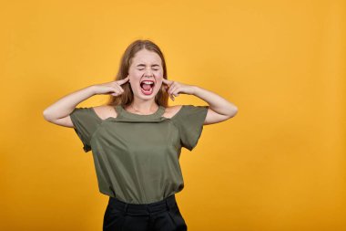 Yanaklarını şişiren ve parmaklarını kızgın suratıyla tutan komik genç bir kadın.