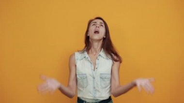 Şok olmuş beyaz kadın mavi kot gömlekli dua ediyor, ellerini açıyor, çığlık atıyor.