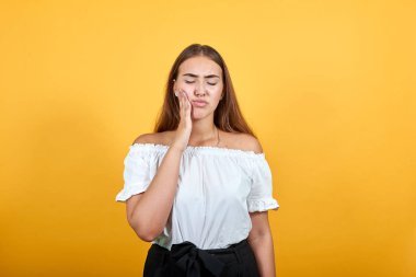 Çekici genç bir kadın. Elleri yanakta, diş ağrısı, acı içinde.