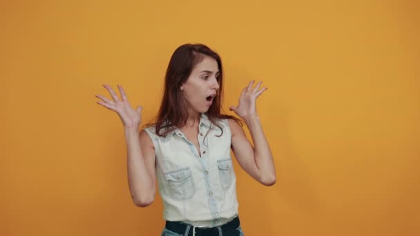 Geschokt jonge vrouw in blauwe denim shirt houden palmen direct, geopende mond — Stockvideo