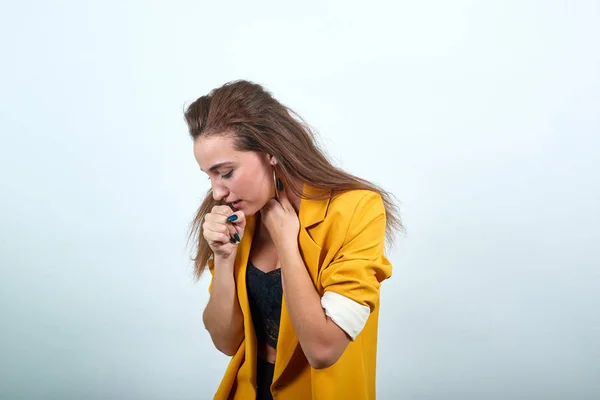 Γυναίκα με κίτρινο σακάκι κρατώντας το χέρι στο στόμα, βήχας, αναζητούν ασθένεια — Φωτογραφία Αρχείου