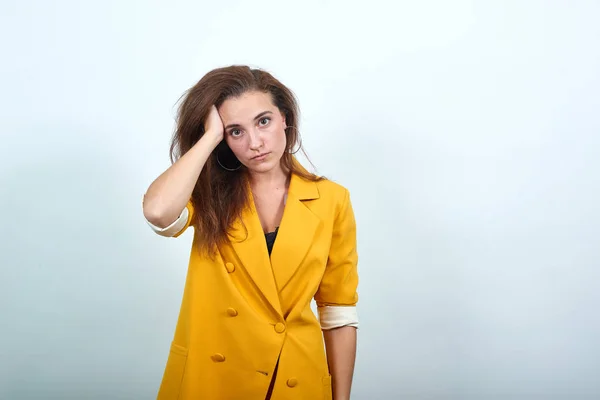 Mad ung kvinna i gul jacka hålla hand på huvud, ser arg — Stockfoto