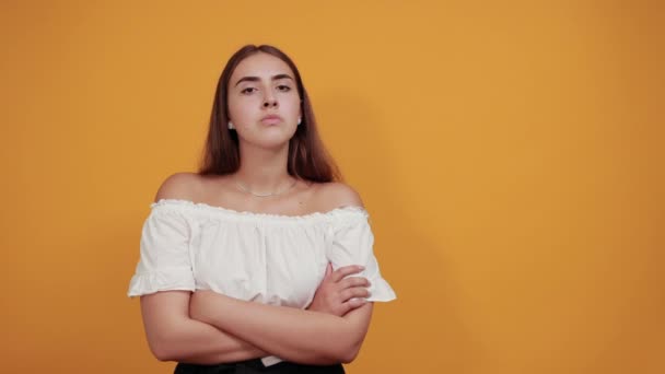 严肃的年轻女子在做停止动作，虱子的姿势被隔离在橙色的墙上 — 图库视频影像