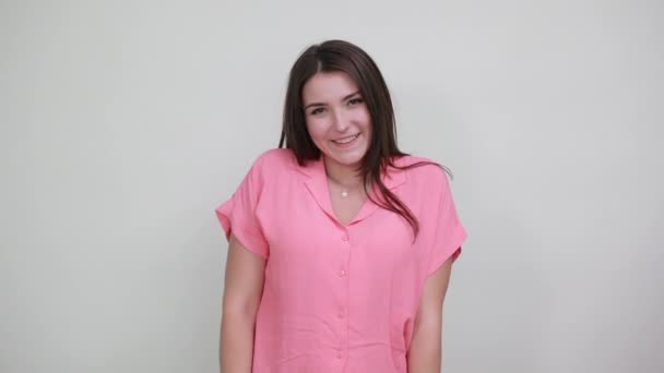 Vrij blanke jonge vrouw in roze shirt doet vorm van hart, ziet er grappig uit — Stockvideo