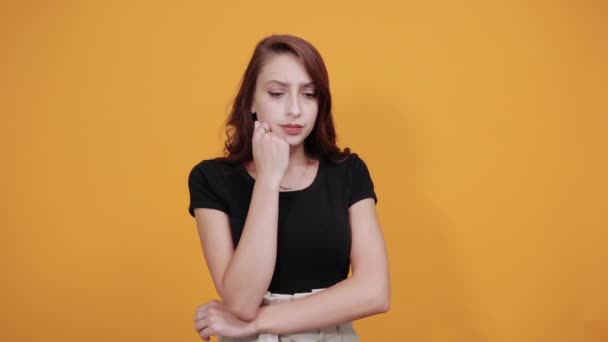 Decepcionada mujer joven caucásica manteniendo la mano en la barbilla, mirando triste, infeliz — Vídeo de stock