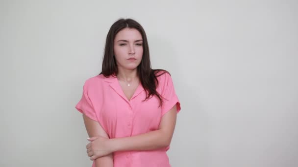 Шокированная молодая женщина в розовой рубашке держит руки на губах, выглядит испуганной — стоковое видео