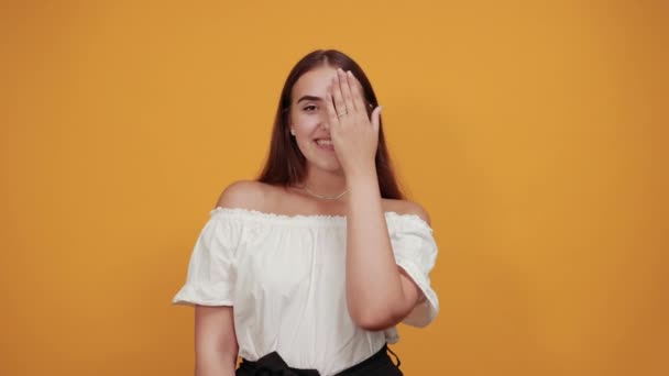 Encantadora morena caucásica cubriendo los ojos con la mano, sonriendo — Vídeo de stock