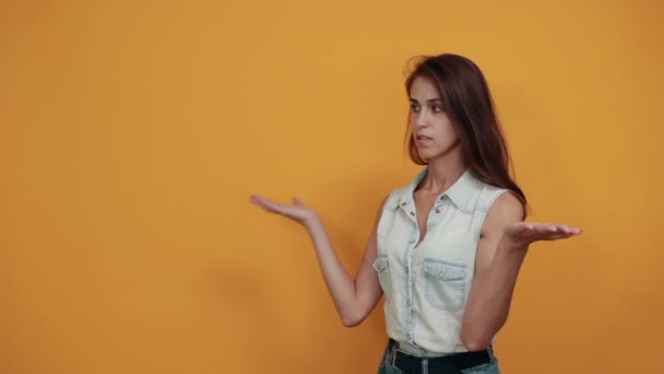 Caucásico atractiva mujer en azul camisa de mezclilla extiende las manos, mirando en serio — Vídeos de Stock