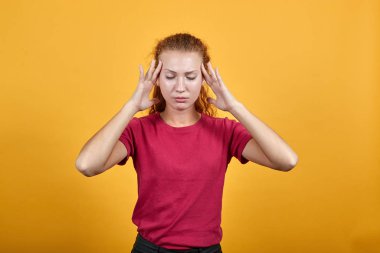 Kırmızı tişörtlü çekici genç bayan ellerini başının üstünde tutuyor, baş ağrısı