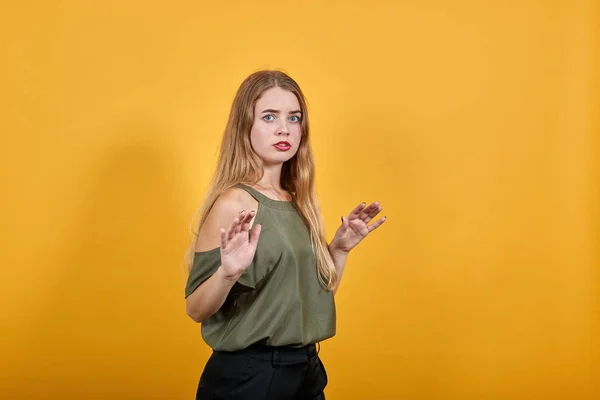 Γυναίκα πάνω από τον πορτοκαλί τοίχο κάνει ασήμαντη χειρονομία σταματήσει, κοιτάζοντας απευθείας — Φωτογραφία Αρχείου