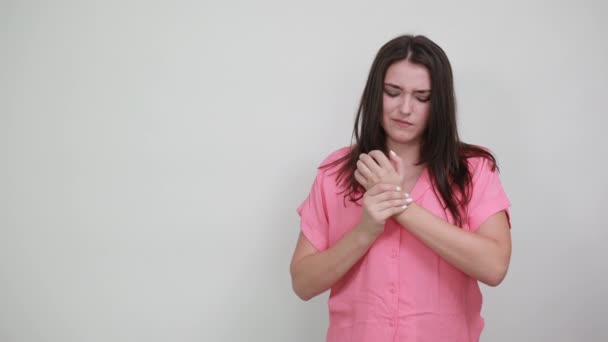 Ennuyeux caucasien jeune femme en chemise rose faire massage sur les mains, l'air triste — Video