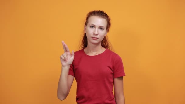 Aantrekkelijke jonge vrouw in rood shirt houdt vinger omhoog met gekruiste vingers — Stockvideo