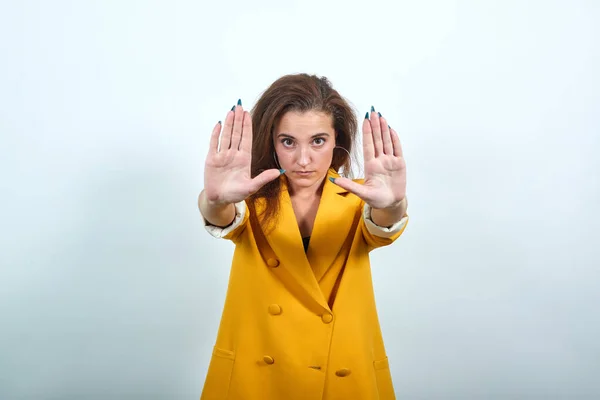 Mladá žena ve žluté bundě nedělá žádné gesto, vypadá nešťastně — Stock fotografie