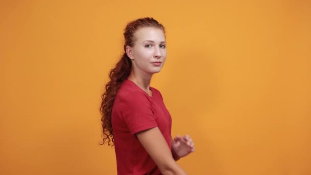 Mooie jonge vrouw in rood shirt hand in hand gekruist kijken opzij — Stockvideo