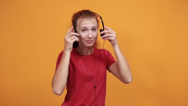 Mosolygó nő piros ingben fülhallgatóval, tartsa rajta a kezét, mosolyogva — Stock videók