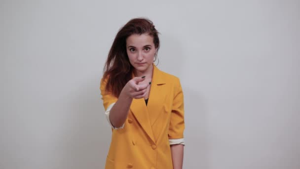 Fröhliche junge Frau in gelber Jacke macht Grußgeste, lädt ein — Stockvideo