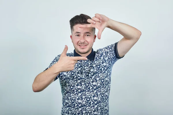 Junger Mann in lässiger Kleidung posiert und macht Hände Fotorahmen Geste. — Stockfoto