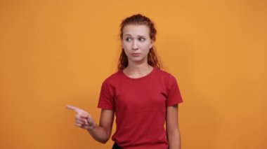 Kırmızı gömlekli güzel bayan hayal kırıklığına uğramış jestler yapıyor, başparmaklarını aşağı gösteriyor.