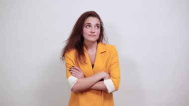 Çekici bir kadın, gri duvarda el ele tutuşup bakıyor.