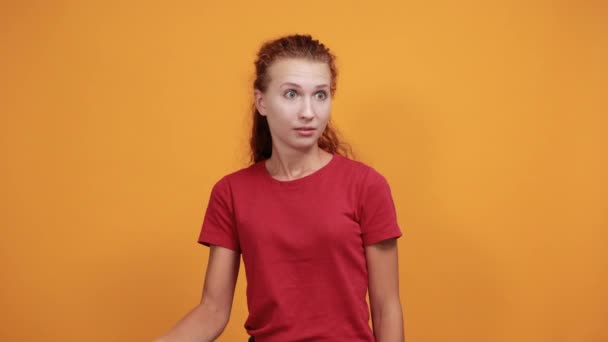 Mujer joven con camisa roja señalándose a sí misma, indagando la expresión facial — Vídeos de Stock