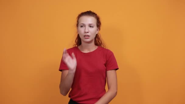 Saaie jonge dame in rood shirt houden hand op kin, na te denken over kwestie — Stockvideo
