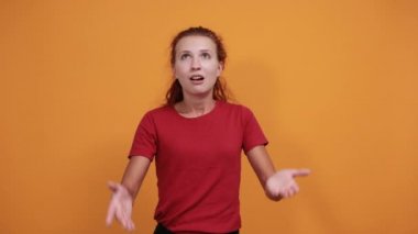 Kırmızı gömlekli güzel bayan ellerini açıyor, şaşkın bakıyor.