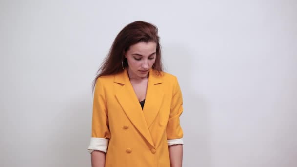 Unhappy young woman in yellow jacket covering mouth with hand, looking in shock — Stock Video