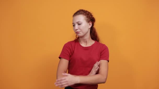 Bonita joven con camisa roja que se ve decepcionada, manteniendo la mano cruzada — Vídeos de Stock