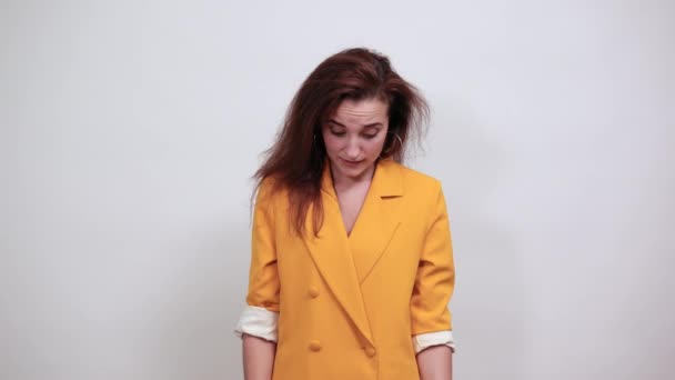 Csinos fiatal nő, sárga kabátban, felnéz, a távolba mutat. — Stock videók