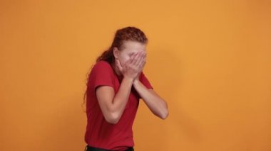 Kırmızı tişörtlü, elleri parmaklarının arasından bakan çekici bir kadın.