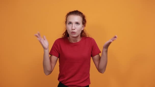 Menina bonita na camisa vermelha espalha braços, olhando entediado, decepcionado — Vídeo de Stock